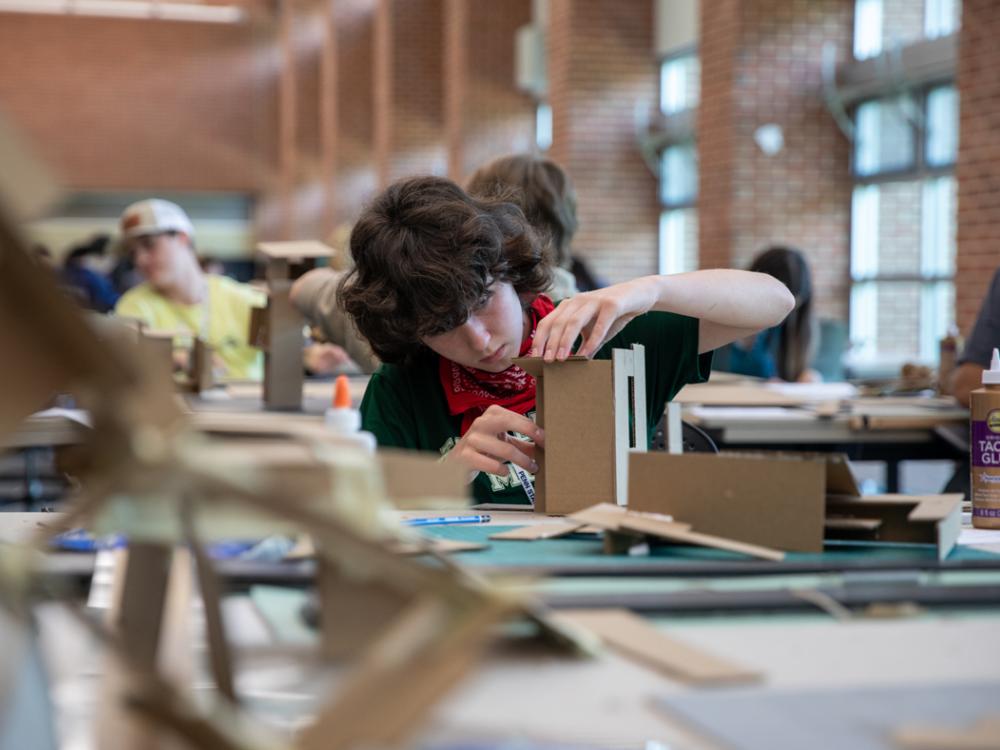 A student building an architectural model out of cardboard.